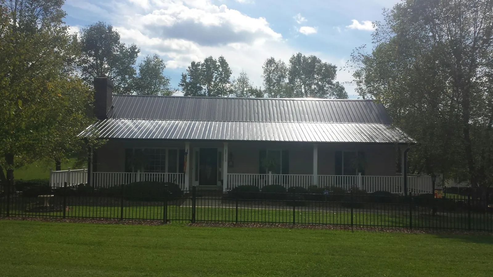 Gray metal roof on a brick ranch with a full width front porch — Gutter Guard Installation work by our crew in Russell